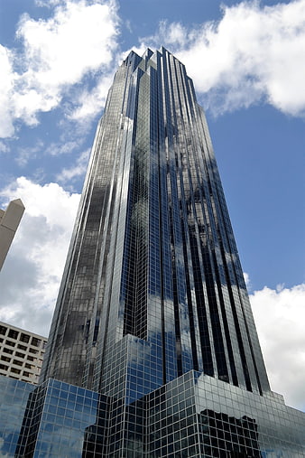 Low angle view of modern glass skyscraper reflecting clouds