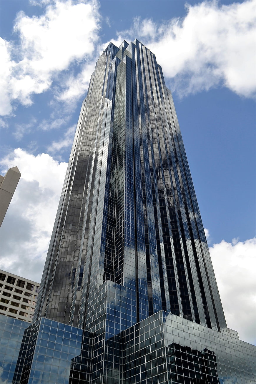 Low angle view of modern glass skyscraper reflecting clouds