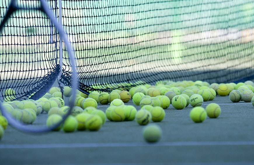 Scattered Tennis Balls On Court With Racket And Net