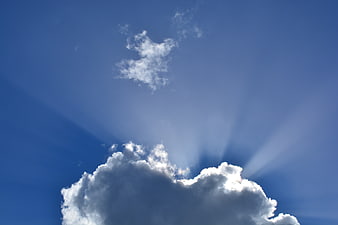 Dramatic Sun Rays Bursting Through White Clouds in Blue Sky
