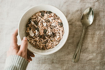 Top View of Hand Holding Bowl of Granola and Spoon