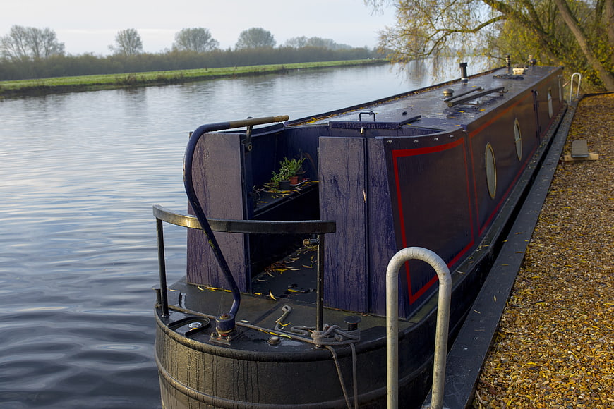 Narrowboat moored on a calm canal in autumn
