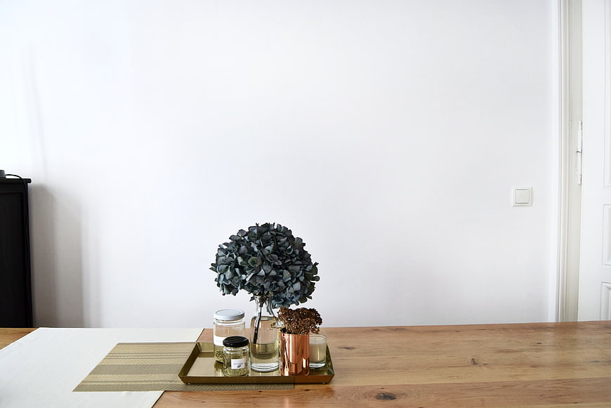 Minimalist wooden table with dried flowers and candles on tray