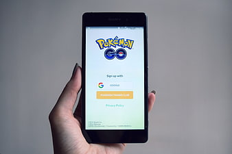 Hand holding smartphone displaying Pokemon Go login screen
