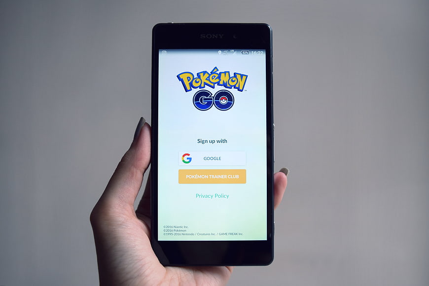 Hand holding smartphone displaying Pokemon Go login screen