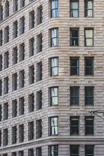 Corner of a beige stone building with repeating window patterns