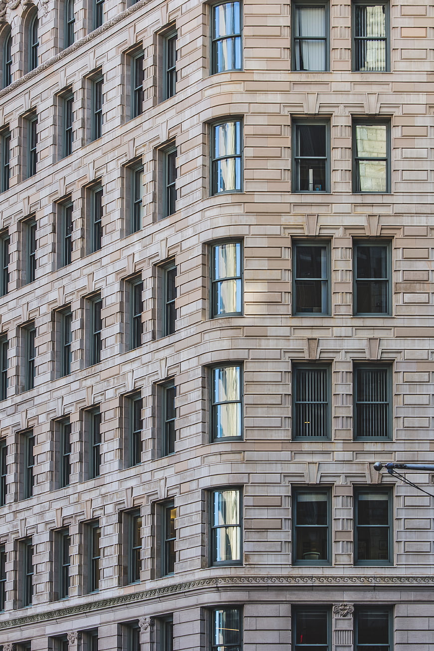 Corner of a beige stone building with repeating window patterns