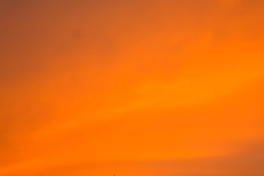 Vibrant Orange Sunset Sky with Soft Clouds Background