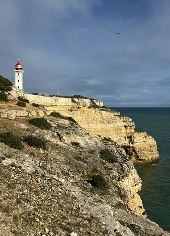 White Lighthouse with Red Top on Rugged Coastal Cliffs