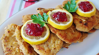 Breaded Pork Schnitzel With Lemon Slices And Cranberry Jam Garnish