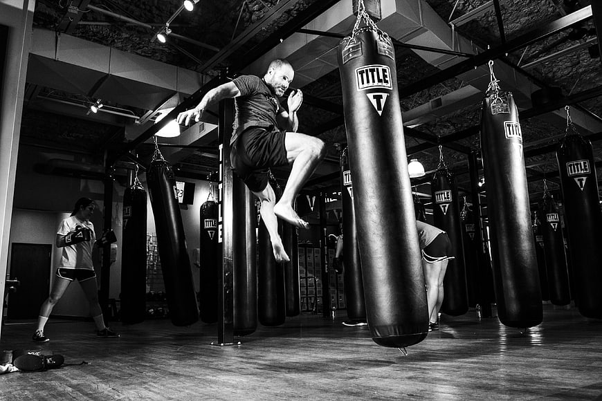 Male martial artist performing high kick in boxing gym