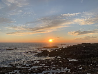 Sunset over rocky ocean coast with clouds