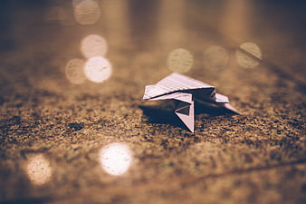 Origami paper crane on textured ground with bokeh