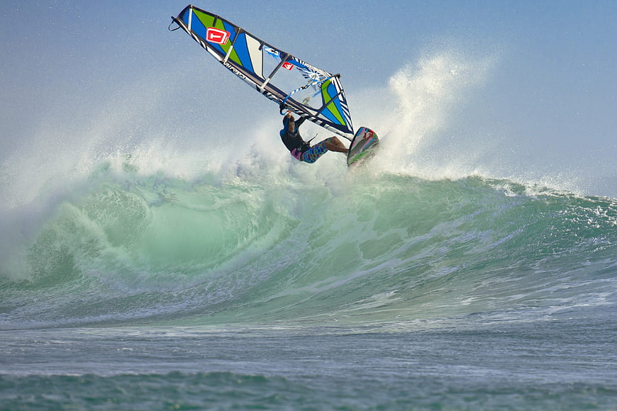 Windsurfer performing an aerial jump on a large ocean wave