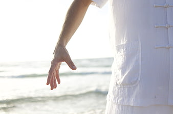 Man practicing Tai Chi on beach in white uniform