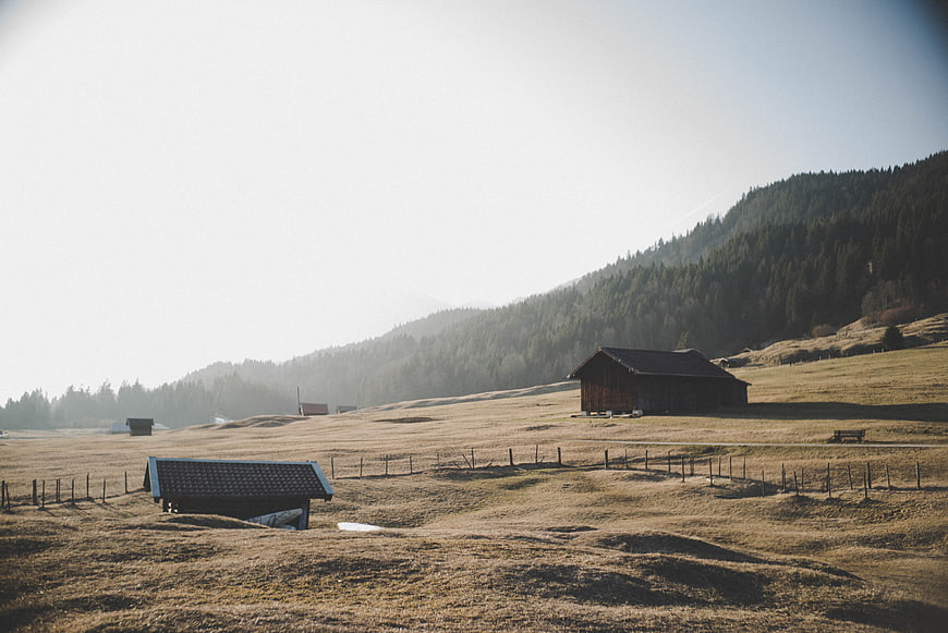 Rustic wooden barns in a sunny alpine meadow landscape