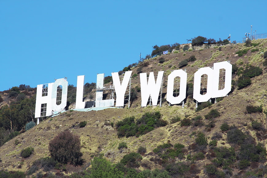 Hollywood Sign on Grassy Hillside Under Clear Blue Sky