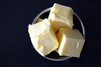 Cubed butter in a metal bowl on dark background