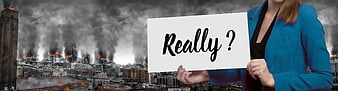 Businesswoman holding 'Really?' sign against burning city background