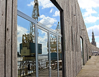 Modern wooden building with glass doors reflecting yellow cranes