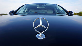 Close-up of Mercedes-Benz Hood Emblem on Blue Car