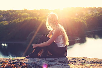 Blonde Woman Sitting by River at Sunset