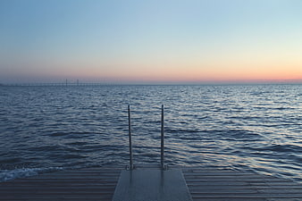 Wooden Dock with Ladder at Sunset Over Calm Water