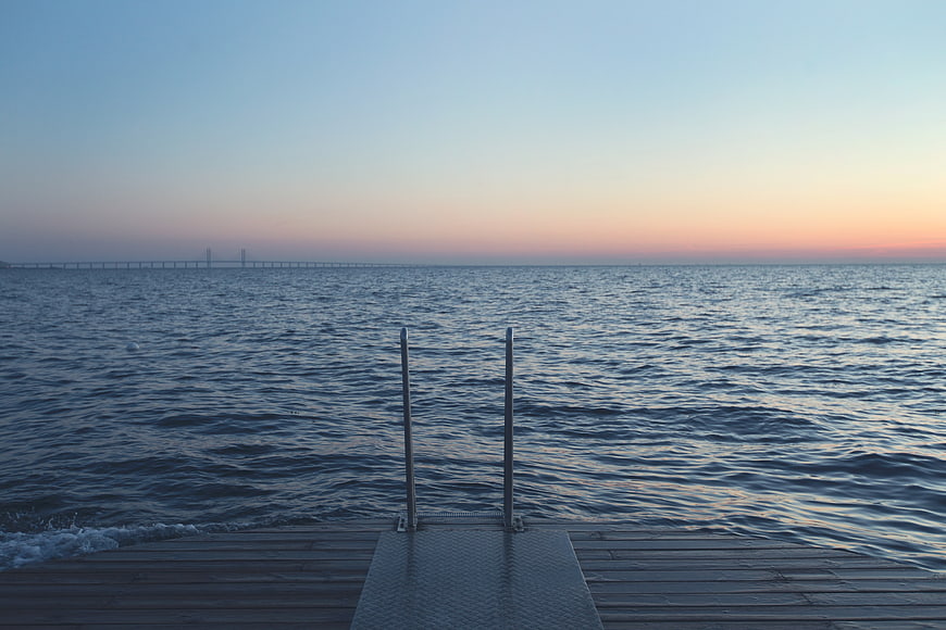 Wooden Dock with Ladder at Sunset Over Calm Water
