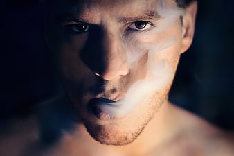 Close-up of man exhaling thick white smoke
