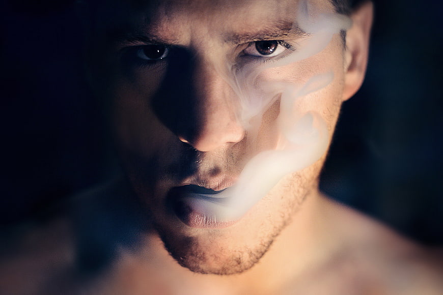 Close-up of man exhaling thick white smoke