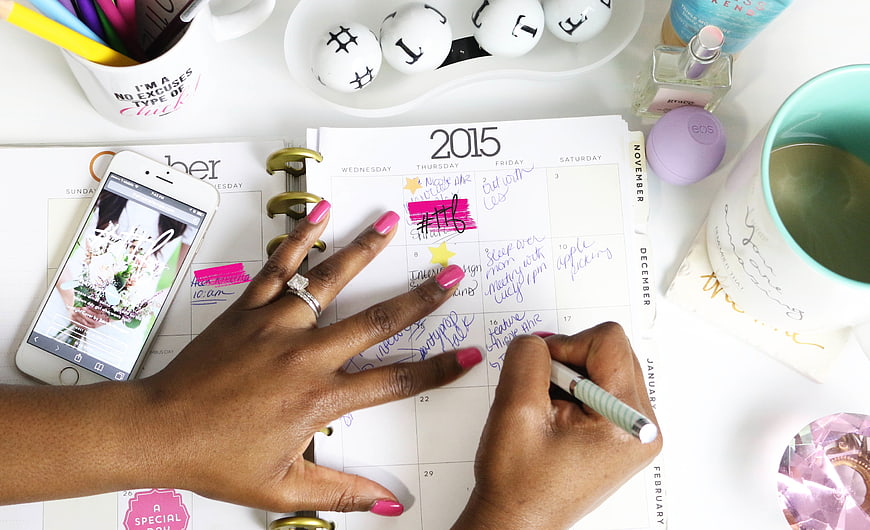 Woman writing in 2015 planner with pink nails and diamond ring