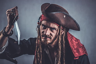 Portrait of a male pirate with dreadlocks holding a dagger