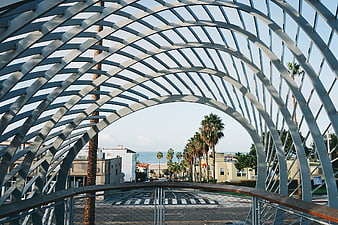 Modern arched metal walkway framing coastal street view