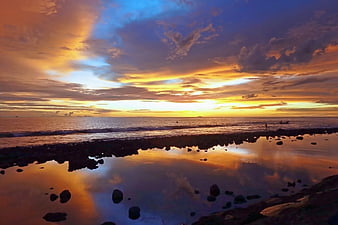 Vibrant Sunset Over Rocky Beach with Tide Pool Reflection