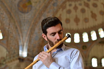 Man playing ney flute in ornate mosque interior