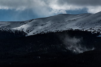 Dramatic Snow-Capped Mountain with Dark Forest and Mist