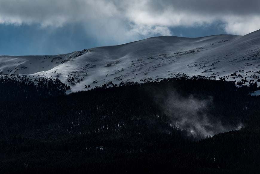 Dramatic Snow-Capped Mountain with Dark Forest and Mist