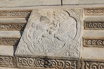 Ancient stone relief carving of a bird on temple steps