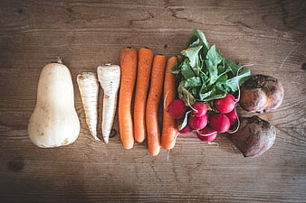 Flat lay of organic root vegetables on rustic wood