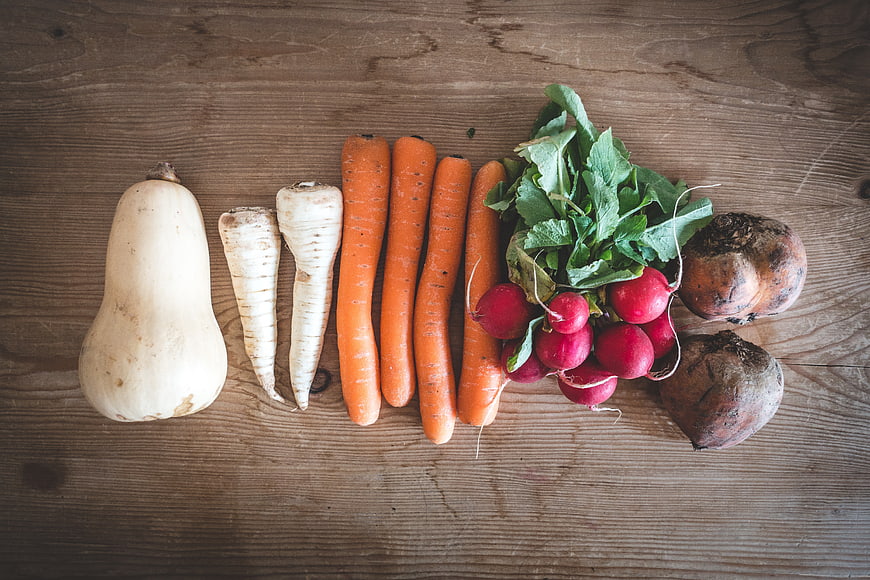 Flat lay of organic root vegetables on rustic wood