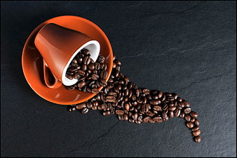 Orange Coffee Cup Spilling Beans on Dark Slate Background