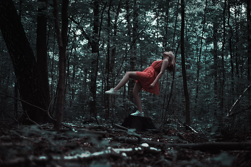 Woman in Red Dress Leaning Back in Dark Forest