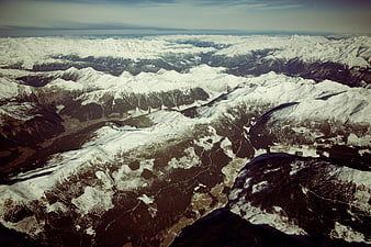 Aerial view of vast snow-covered mountain range with deep valleys