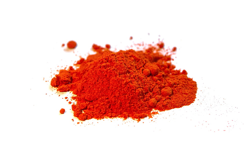 Pile of vibrant red paprika spice powder on white background
