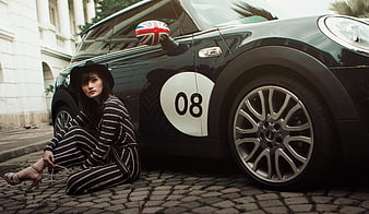 Fashionable Woman Sitting by Black Mini Cooper on Cobblestone Street