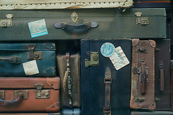 Vintage suitcases with travel stickers stacked in a pile