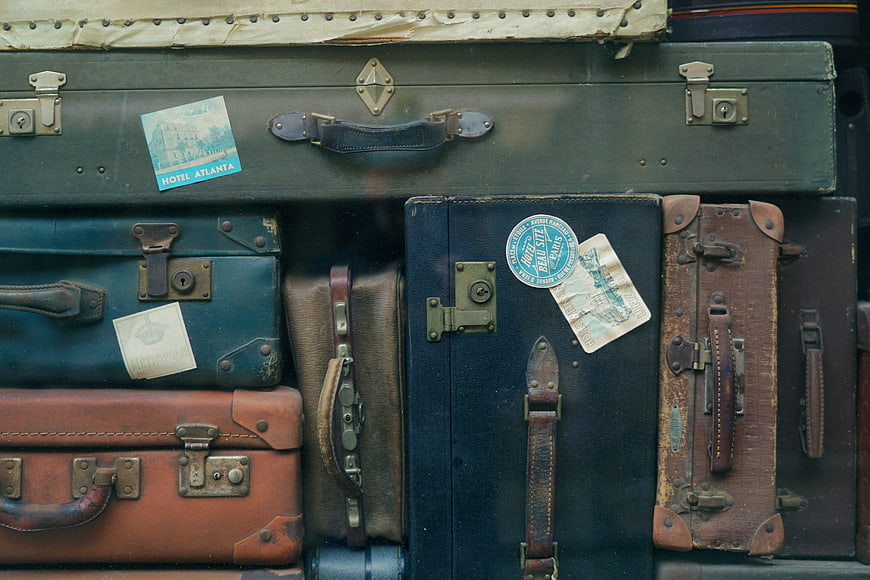 Vintage suitcases with travel stickers stacked in a pile