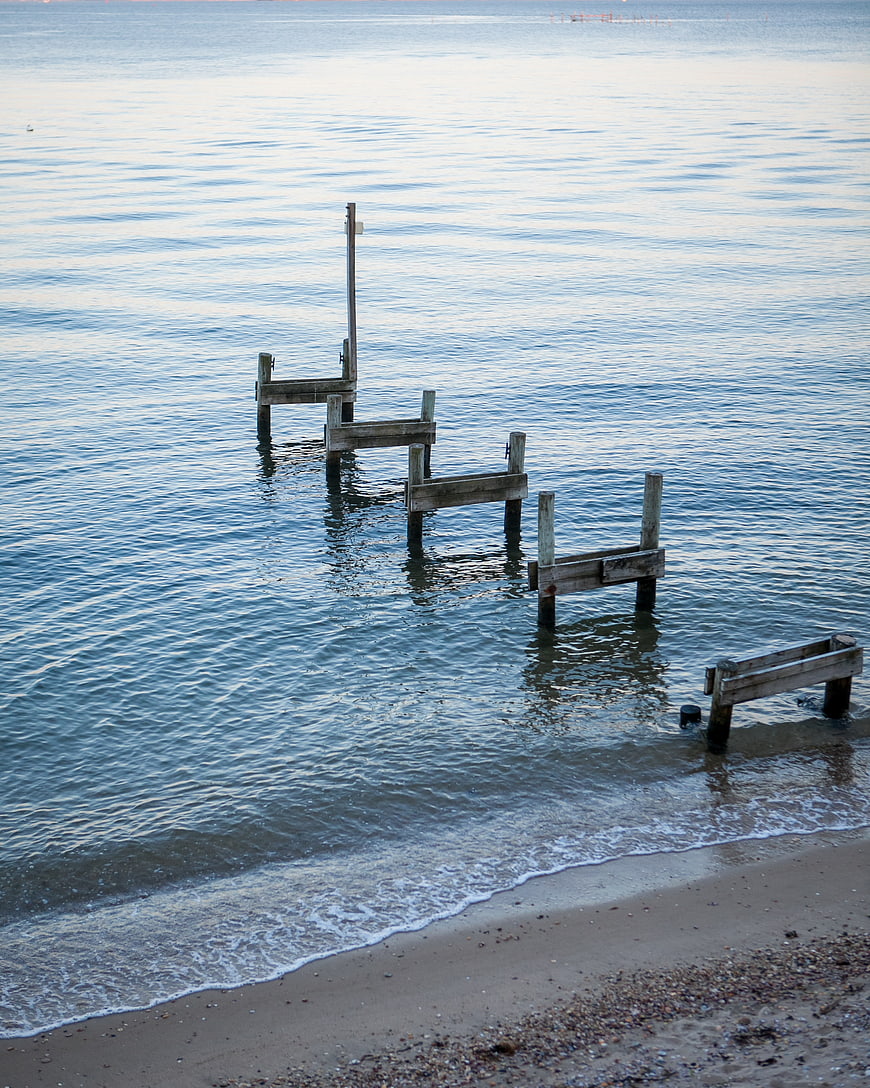 Weathered wooden pier remnants on a calm sandy beach