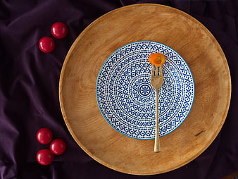 Top view of blue patterned plate with cherry tomato on fork
