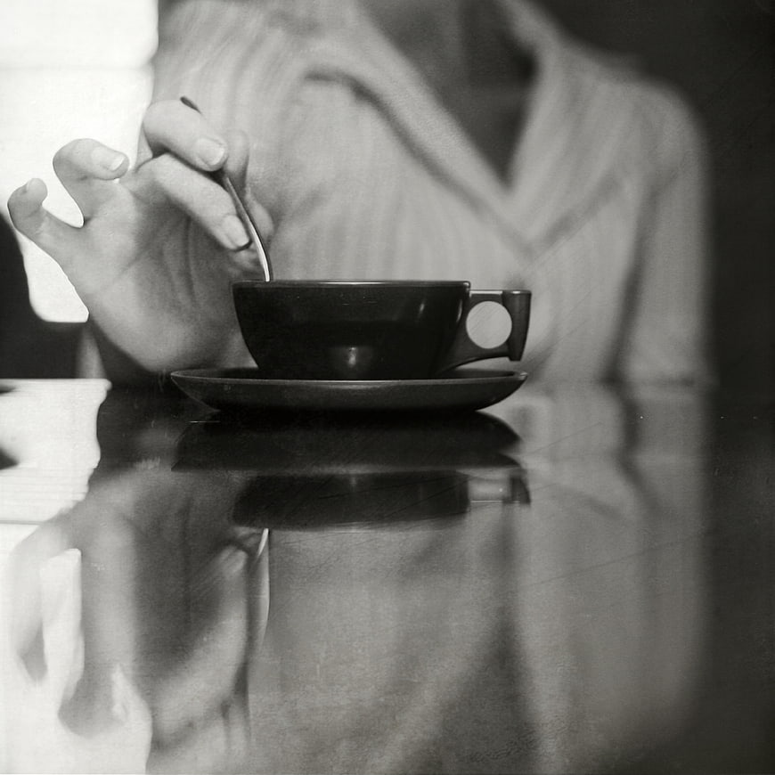 Black and white photo of hand stirring coffee cup